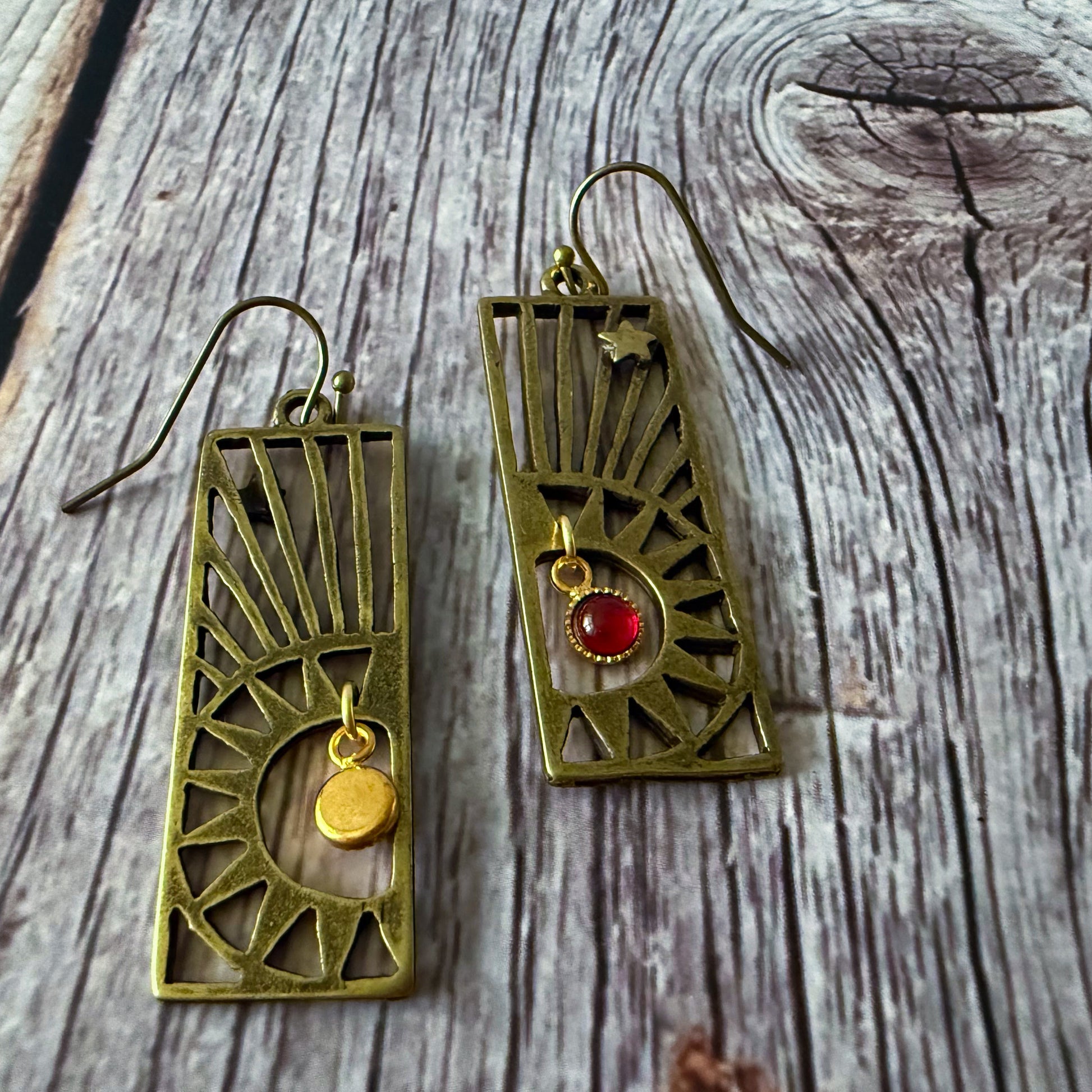 Pair of bronze earrings with birthstones on a wooden surface