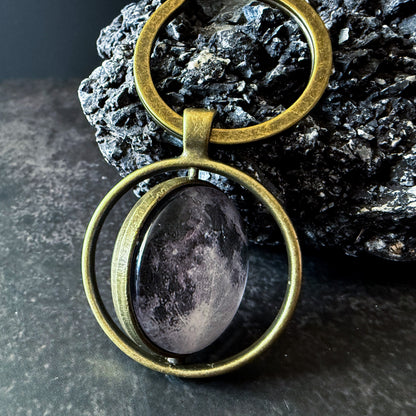 Bronze Keychain leaning on a dark textured rock.