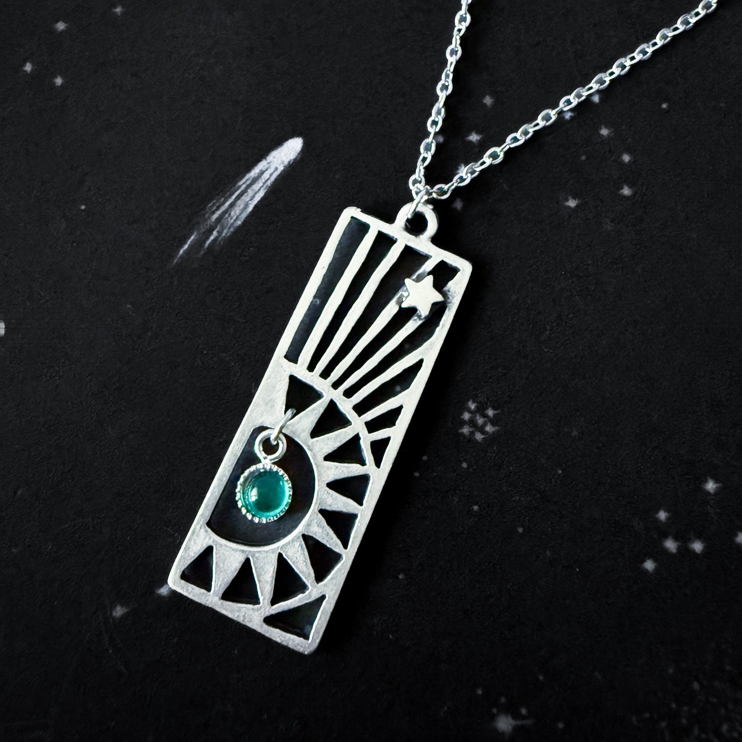 Silver necklace with a rectangular pendant featuring a birthstone on a black background