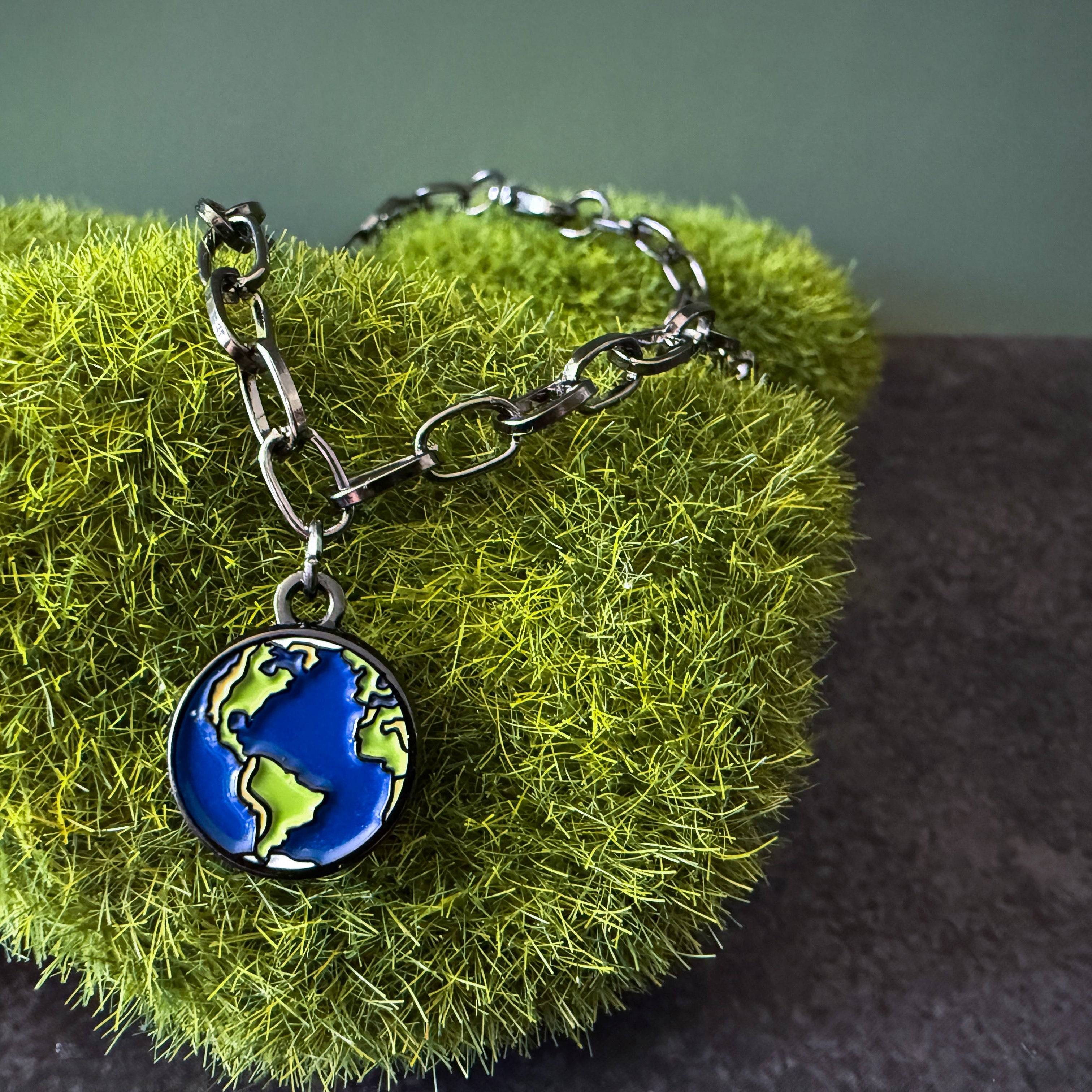 Bracelet with an earth charm on a green textured surface