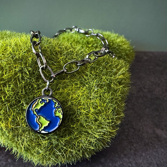 Bracelet with an earth charm on a green textured surface