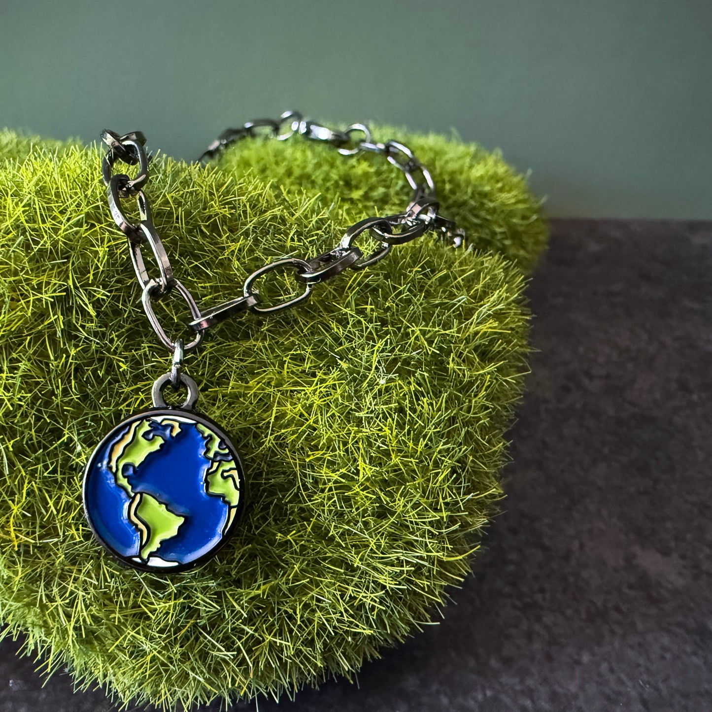Bracelet with an earth charm on a green textured surface