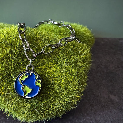 Bracelet with an earth charm on a green textured surface