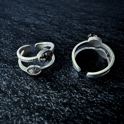 Two silver rings with meteorite fragments on a dark textured surface