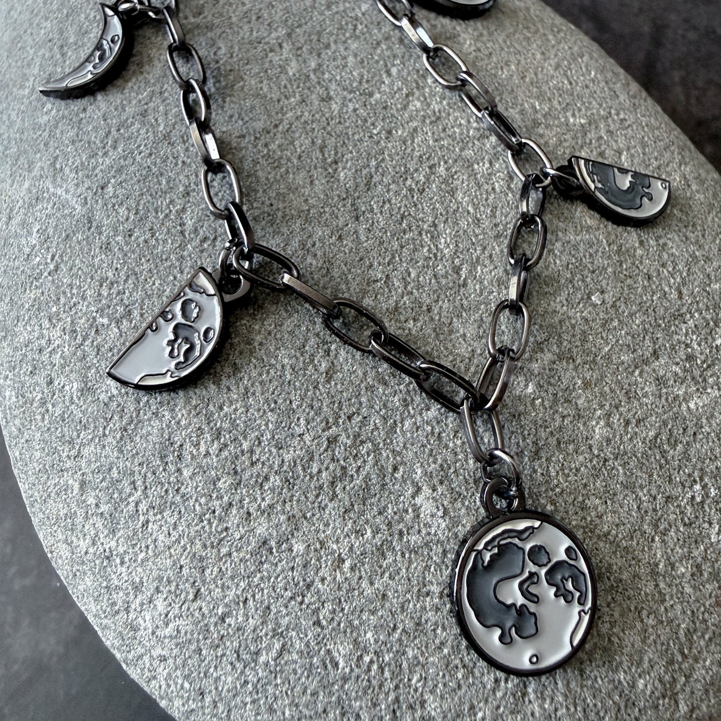 Silver necklace with moon and crescent charms on a stone surface