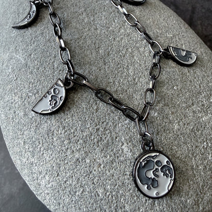 Silver necklace with moon and crescent charms on a stone surface