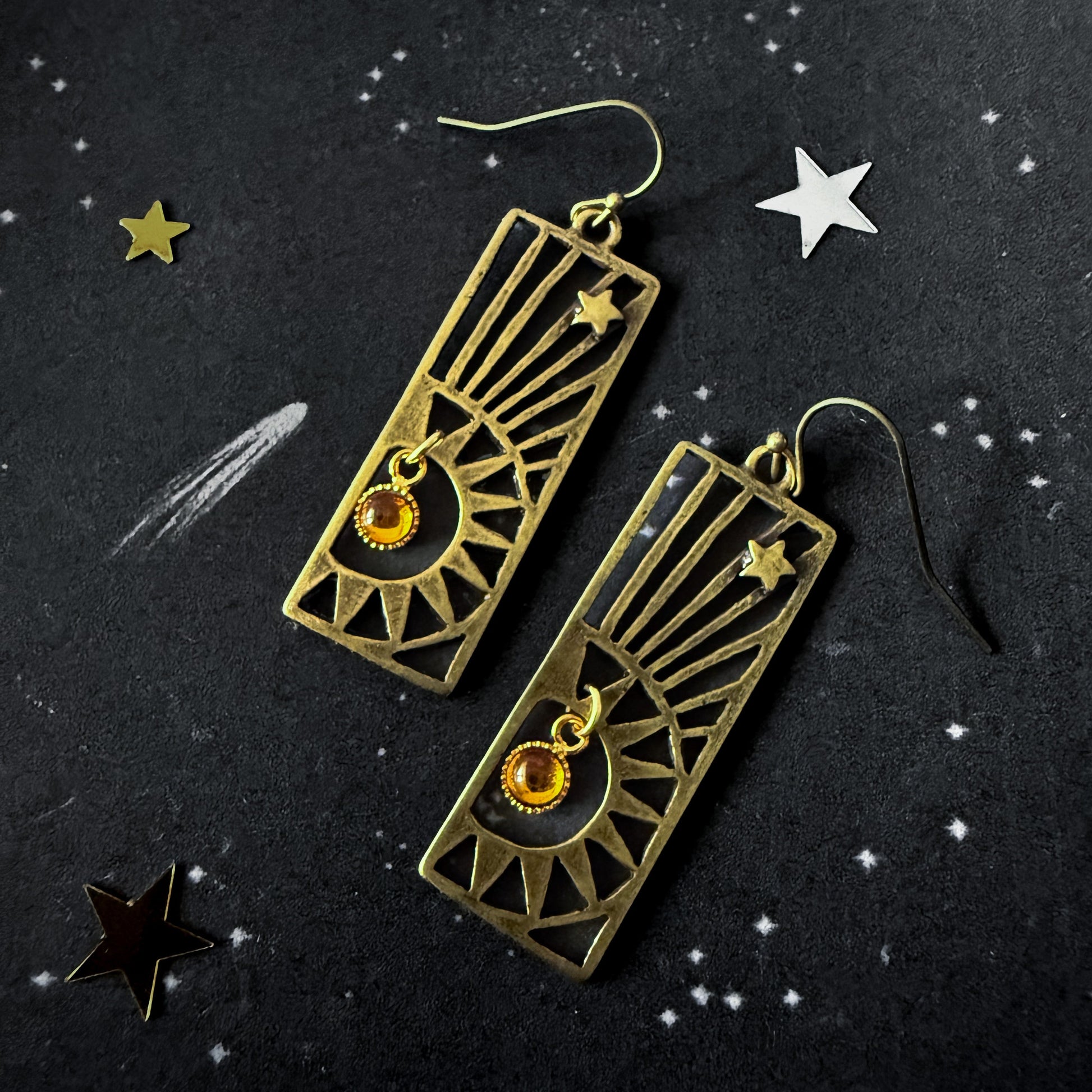 Pair of bronze earrings with star designs on a dark background