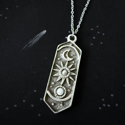 Silver pendant necklace with celestial design on a black background