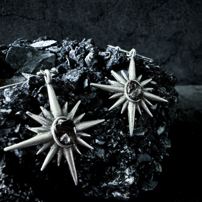 Supernova Starburst Dangle Earrings with Authentic Meteorite siting on a large dark rock