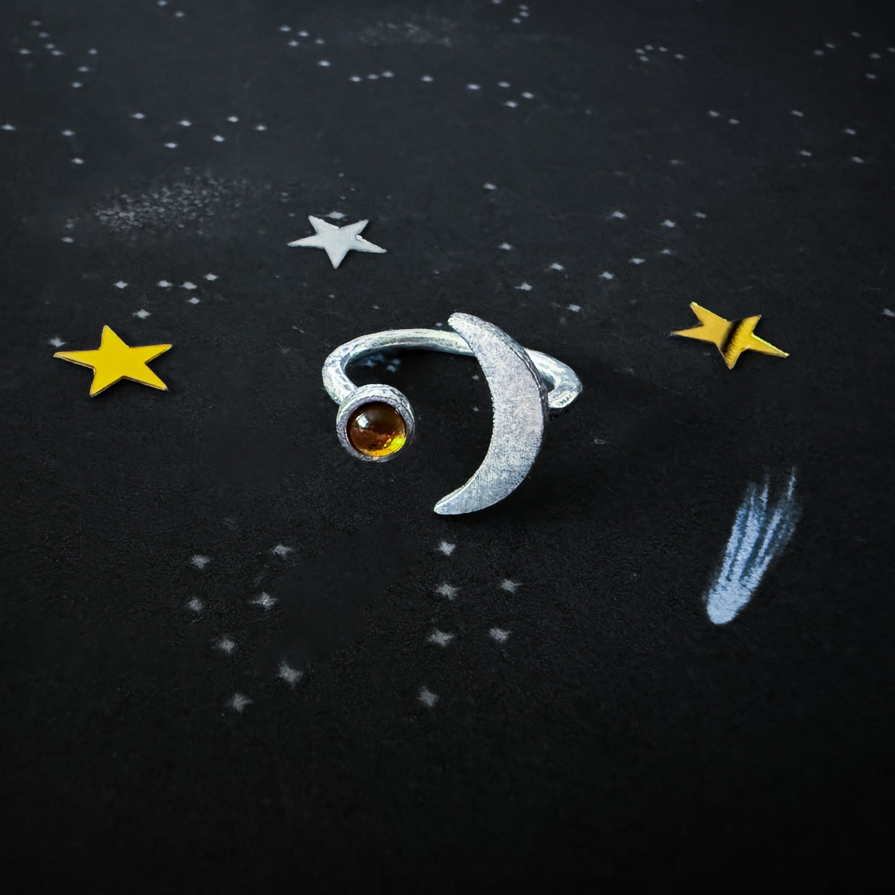 Silver ring with a birthstone on a dark background with star decorations