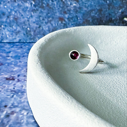 Silver ring with a birthstone on a textured blue surface