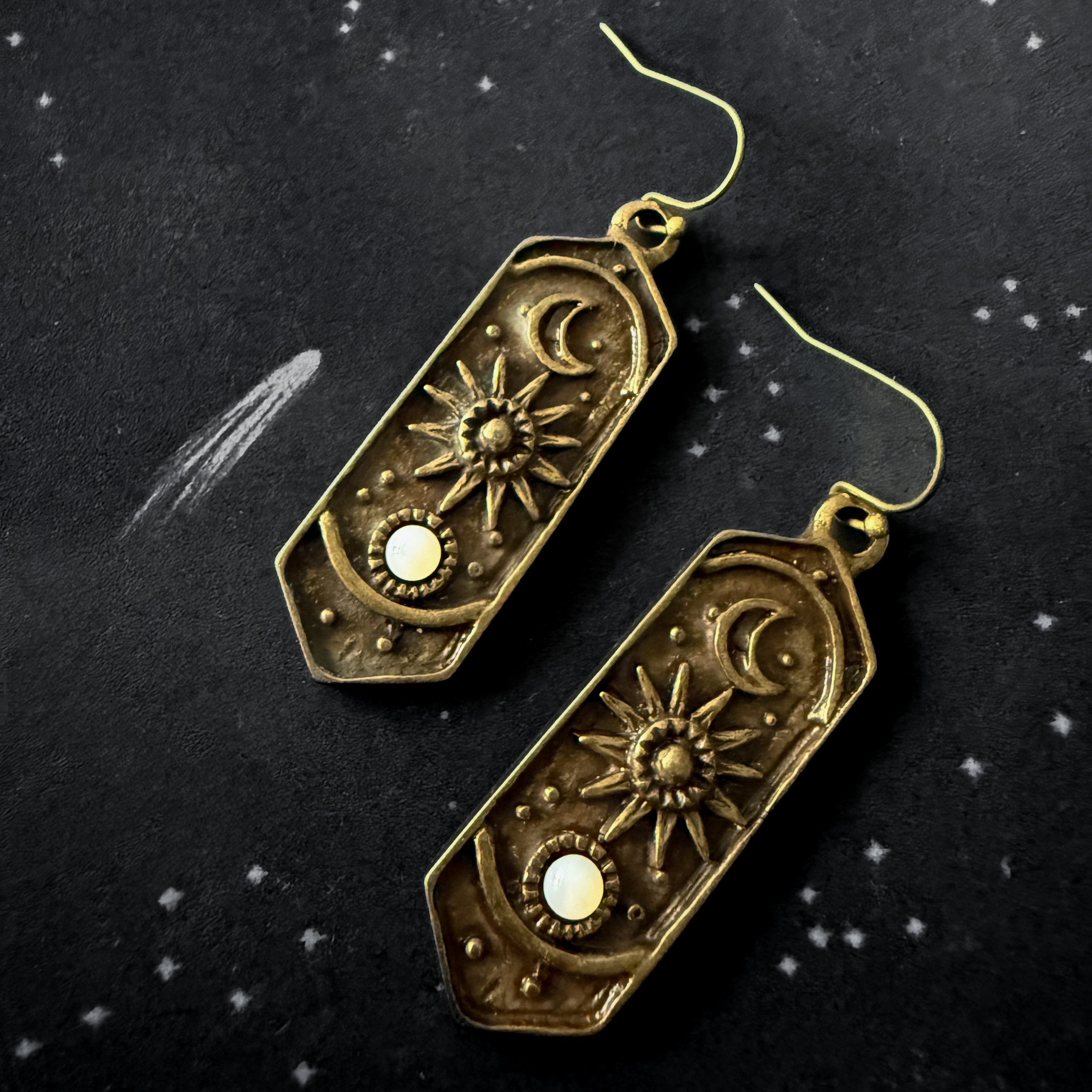Pair of bronze celestial-themed earrings on a dark background