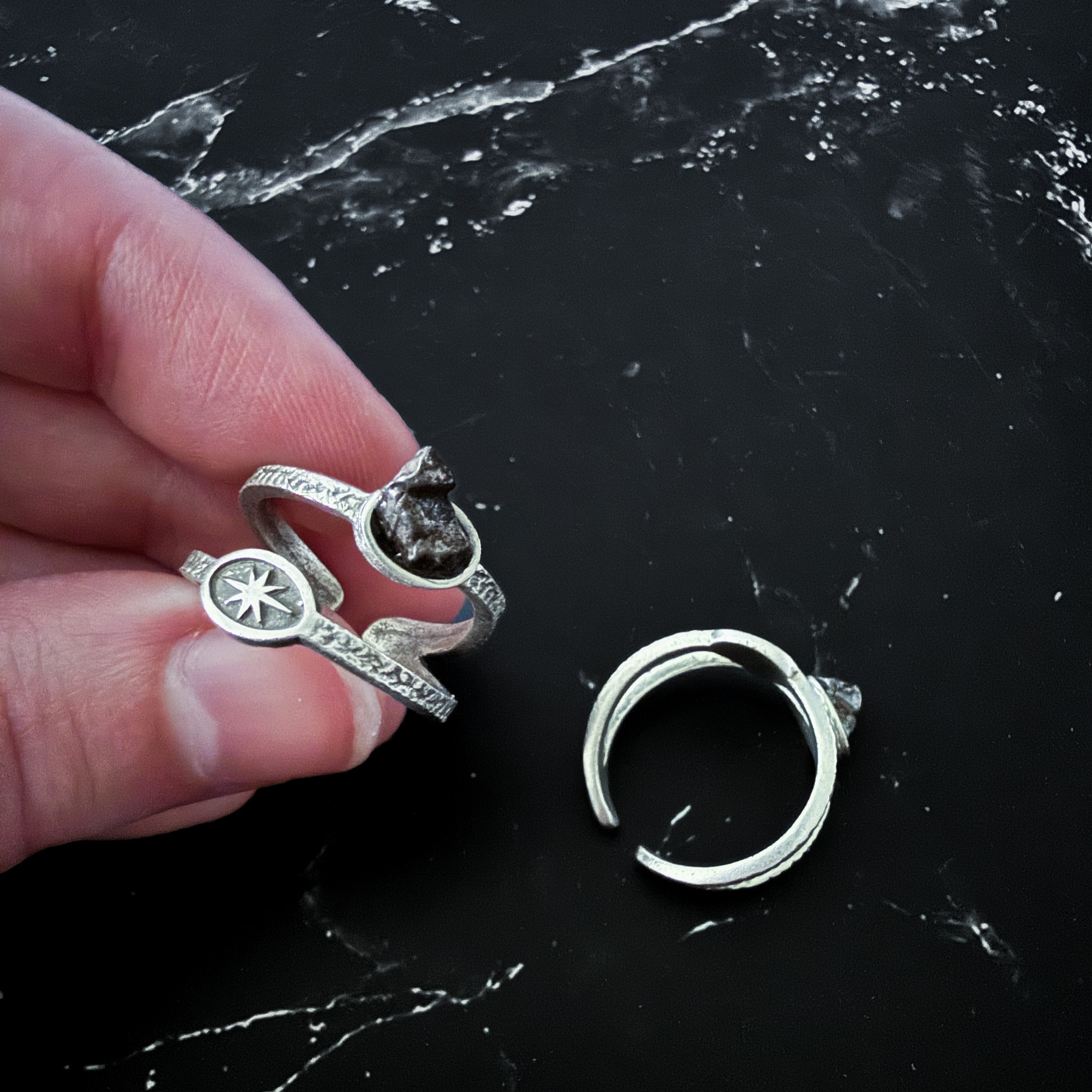 Silver rings on a black marble surface