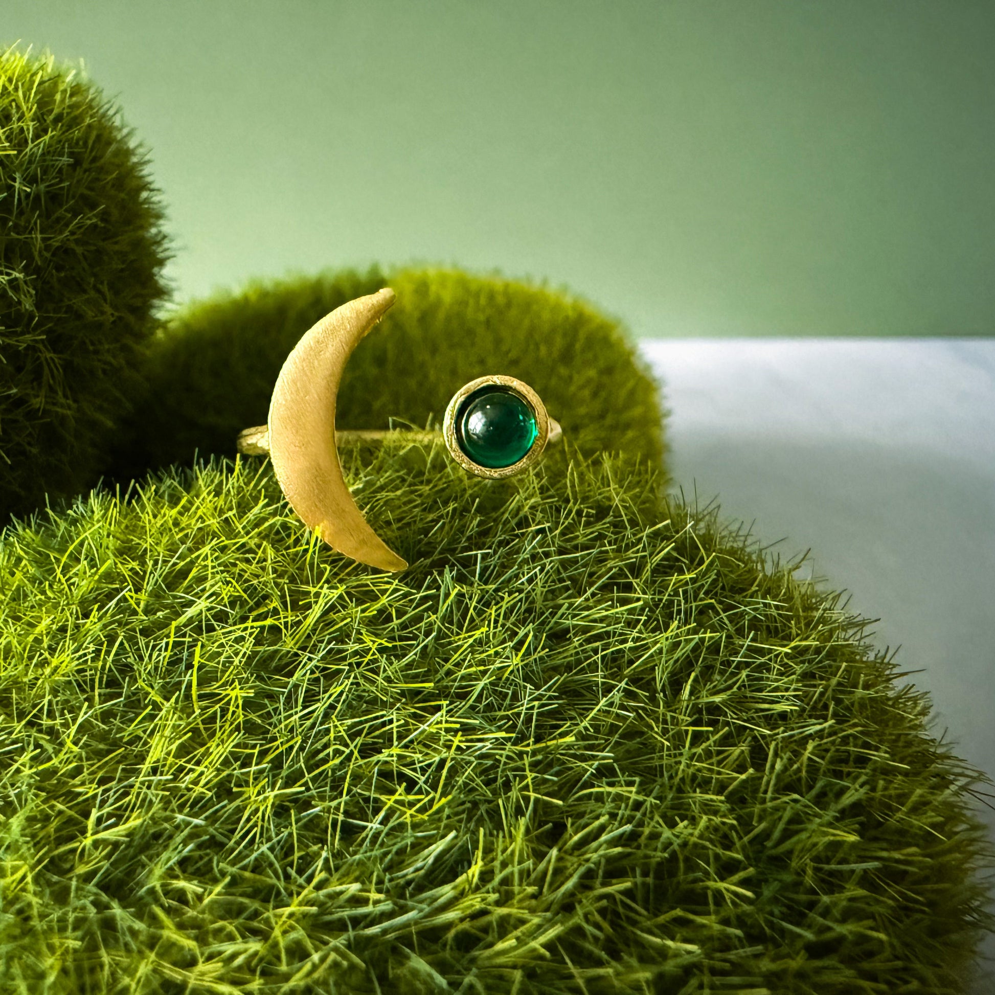 Ring with a birthstone on a textured green surface