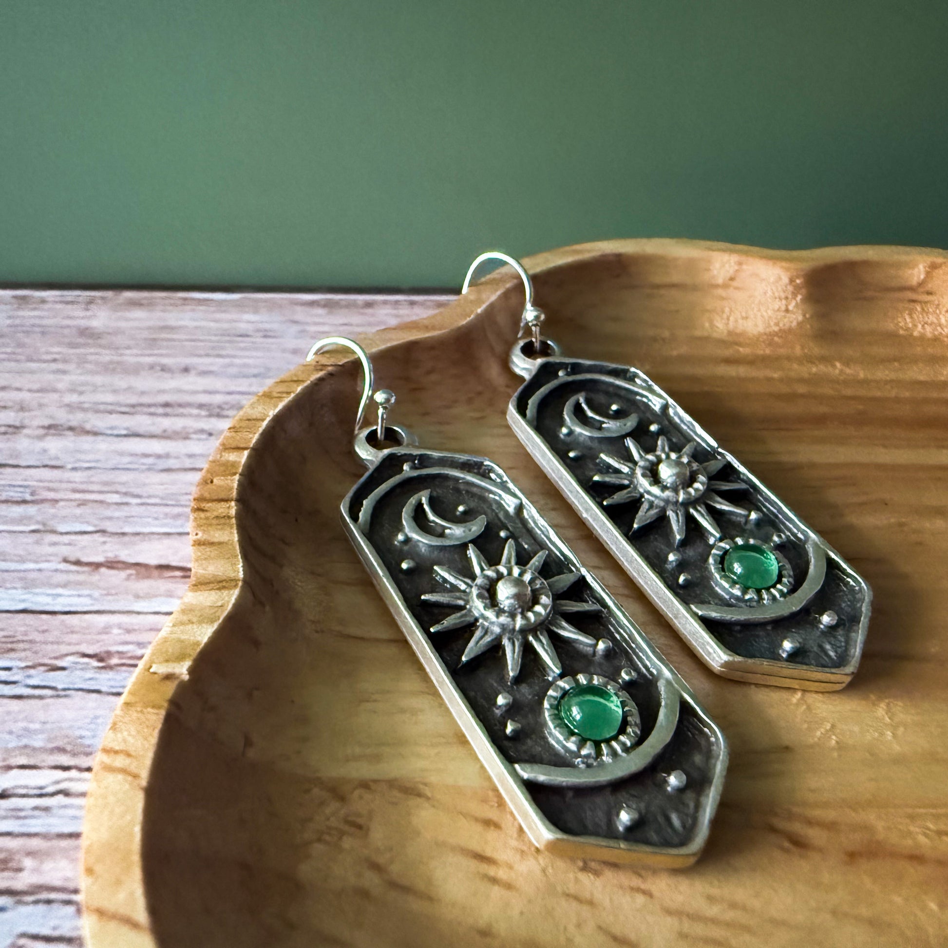 Silver earrings with birthstones on a wooden surface
