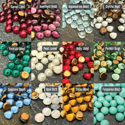 Collection of gemstones representing each month's birthstone on a dark background.