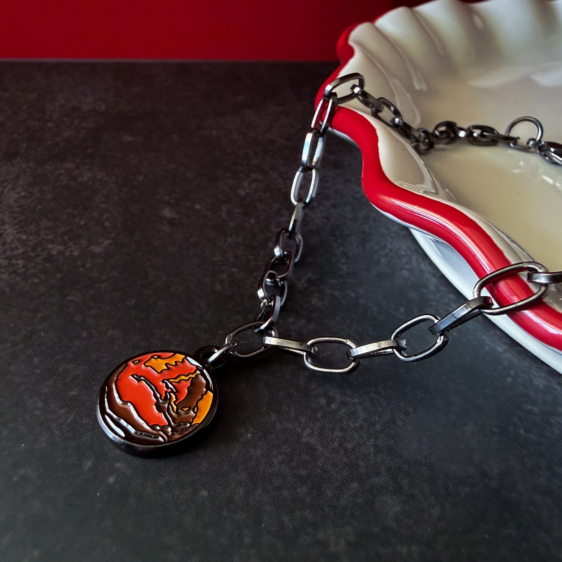 Bracelet with a round mars charm on a dark surface.