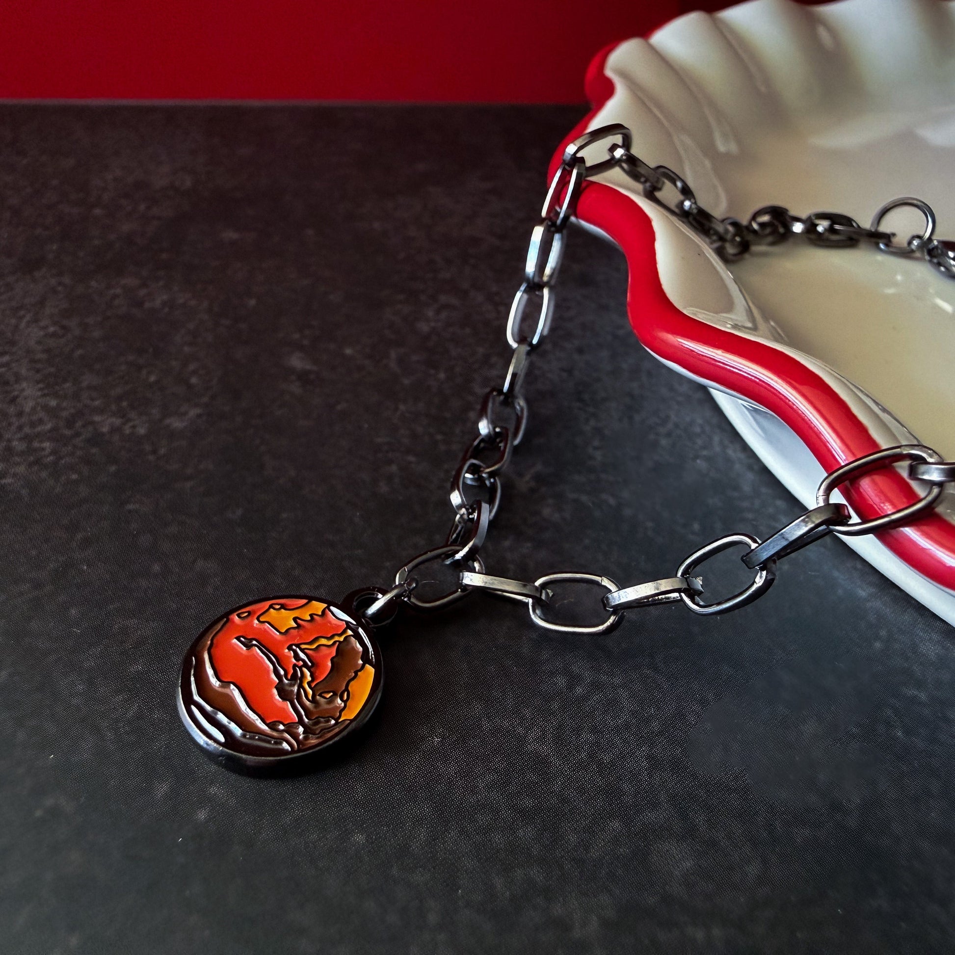 Bracelet with a round mars charm on a dark surface.