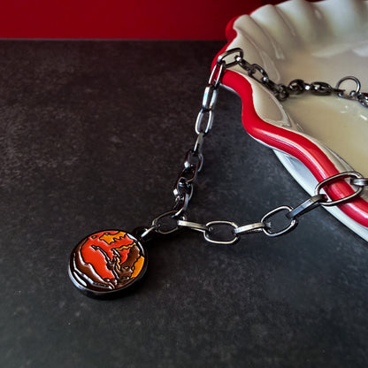 Bracelet with a round mars charm on a dark surface.