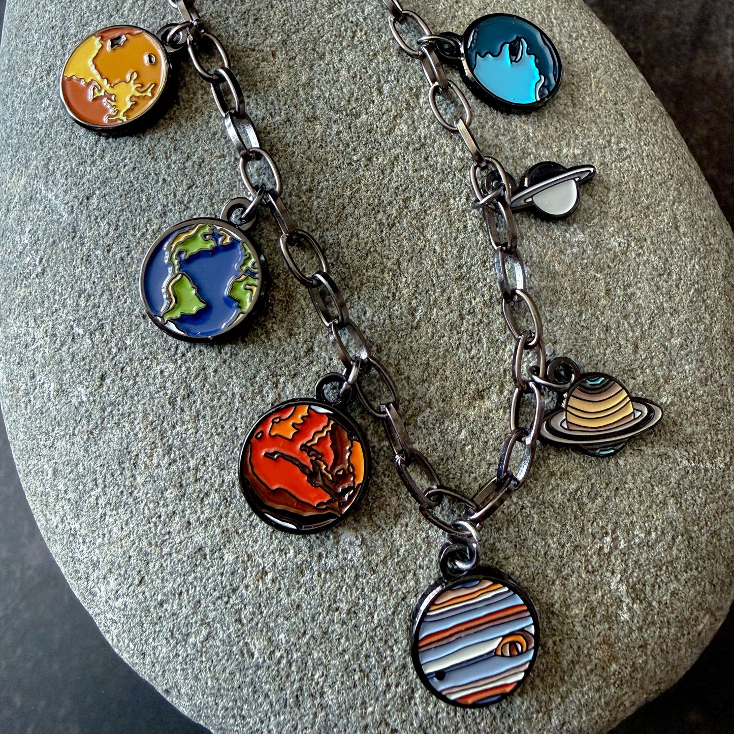 Necklace with solar system charm pendants on a stone surface