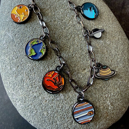 Necklace with solar system charm pendants on a stone surface