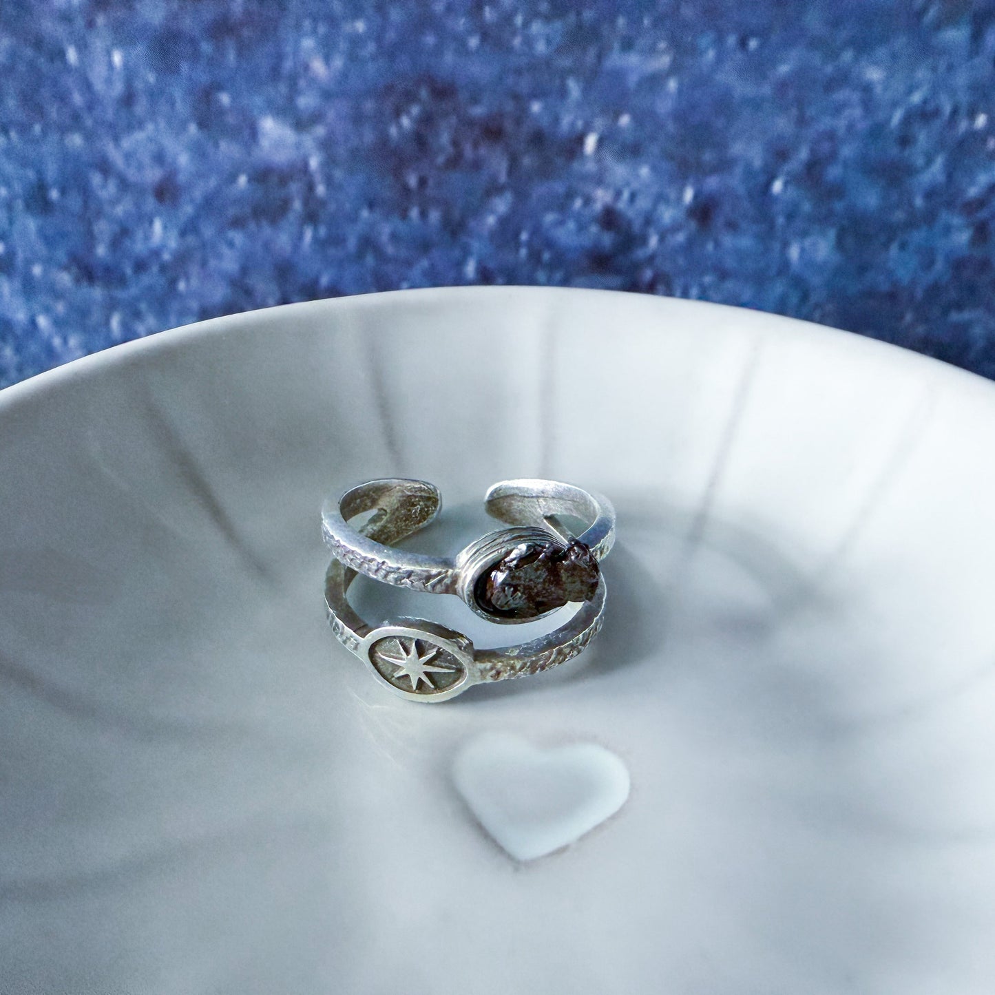 Silver ring on a white dish with a blue textured background