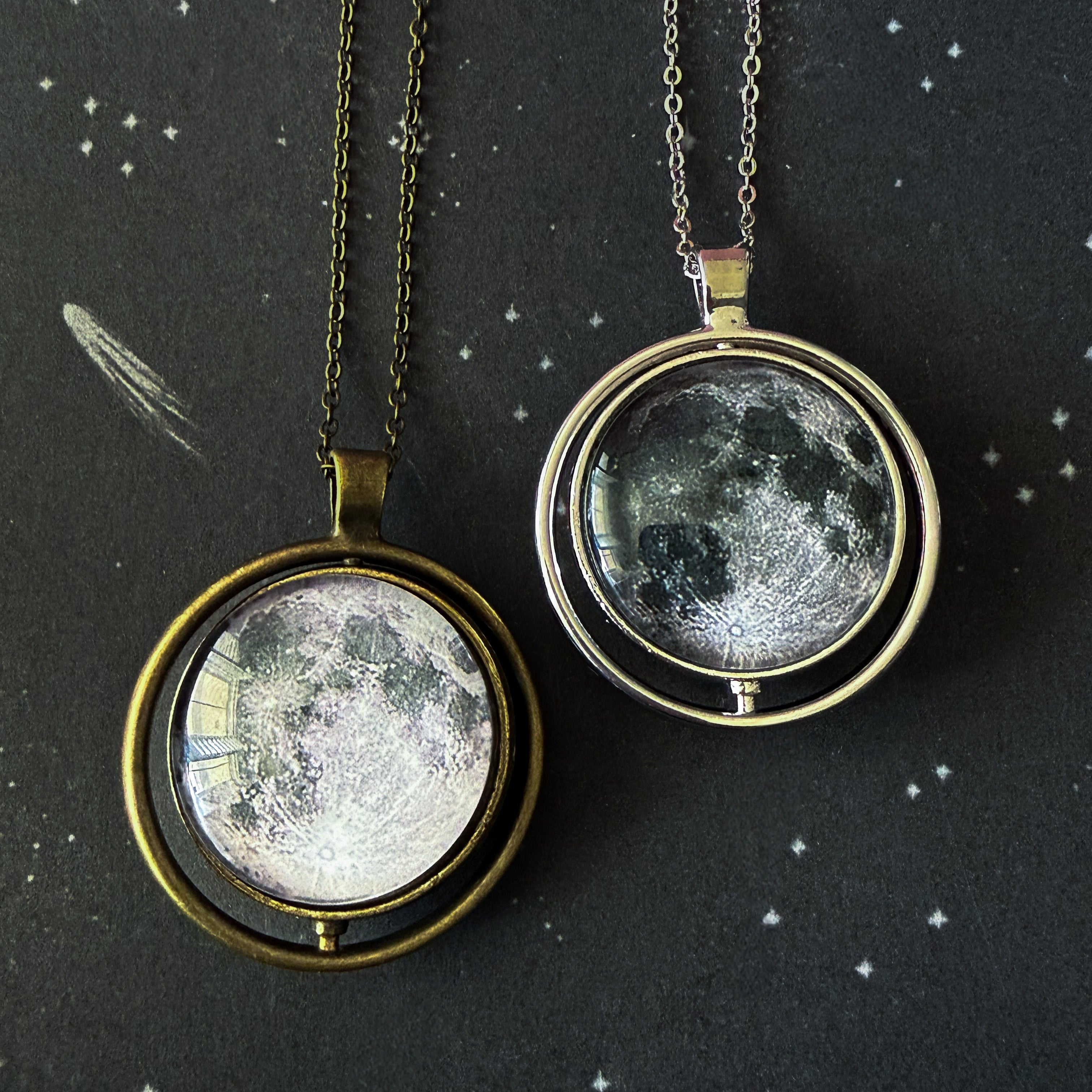 Two moon phase pendants on chains against a starry night sky background.