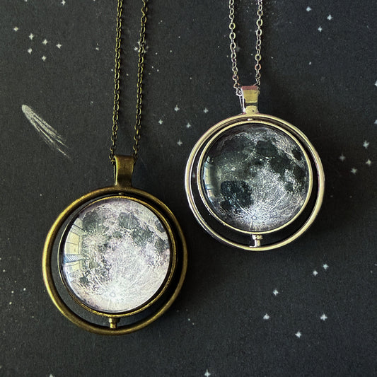 Two moon phase pendants on chains against a starry night sky background.