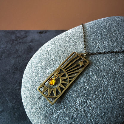 Bronze pendant with a birthstone on a stone surface