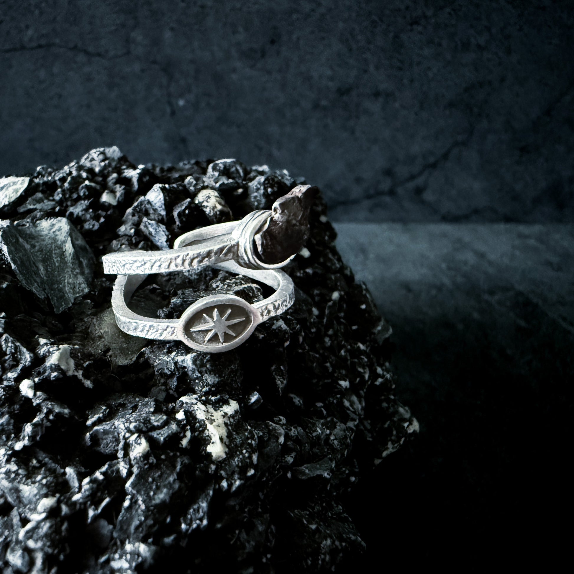 Silver ring with a star design on a dark stone surface
