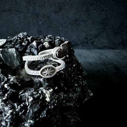 Silver ring with a star design on a dark stone surface