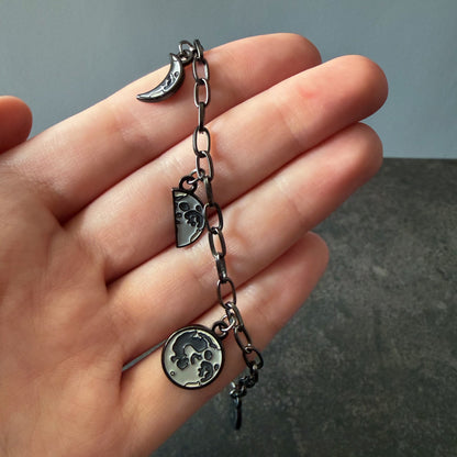 Hand holding a bracelet with Moon Phase charms against a neutral background