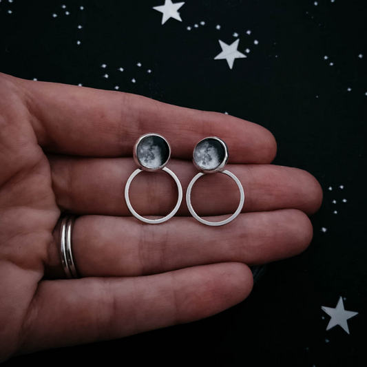 Circle Ear Jacket Earrings of waning gibbous moons being held by a hand
