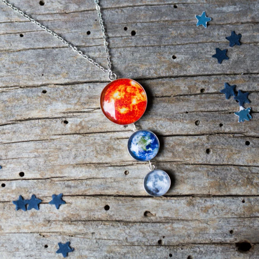 Necklace with Sun, Earth and Moon images on a wooden background with blue star confetti.