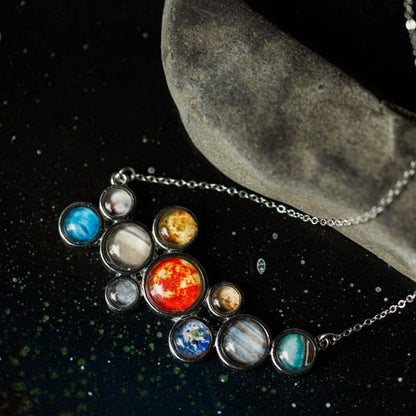 Necklace with solar system pendant on a dark background