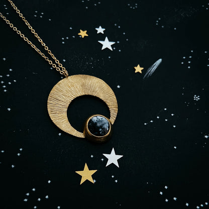 Gold necklace with a circular pendant on a starry night background