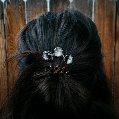 Close-up of a hair bun with decorative hairpins against a wooden background
